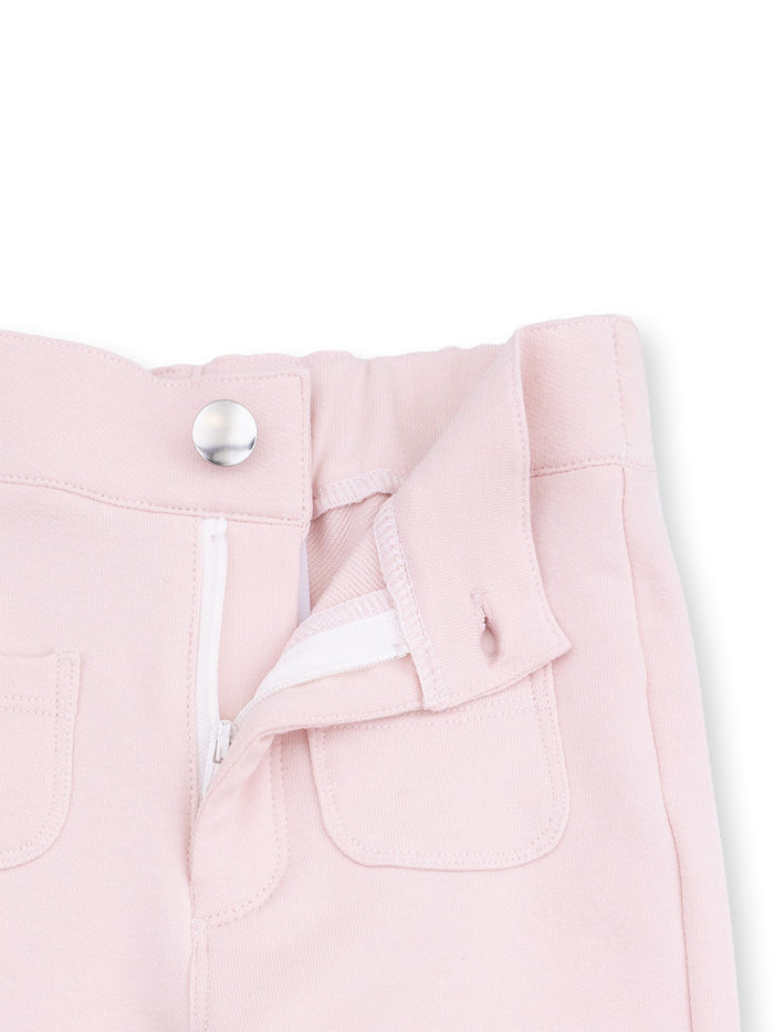 Light pink pants with a zippered front and two small pockets, featuring a silver button closure.