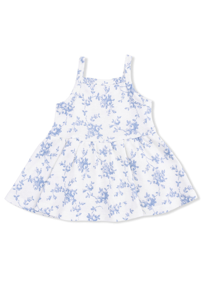 White dress with blue floral pattern and spaghetti straps, featuring a flared skirt. Perfect for summer wear.