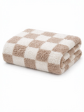 Folded beige and white checkered towel on a white background. Soft texture suitable for bath use.