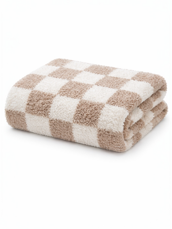 Folded beige and white checkered towel on a white background. Soft texture suitable for bath use.