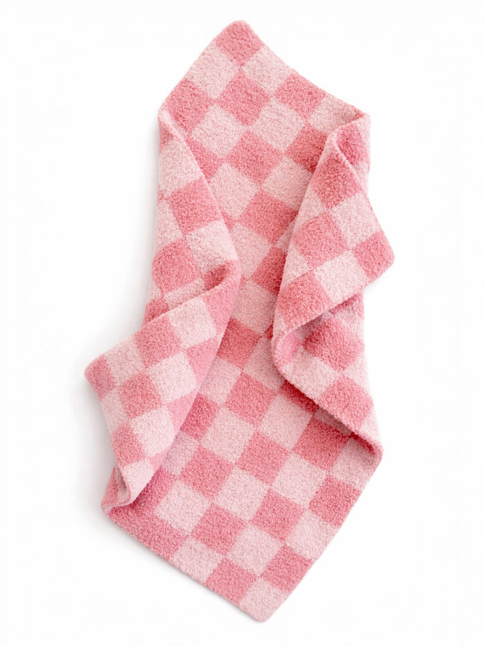 Pink checkered towel folded artistically on a white background. Soft texture and cozy design.
