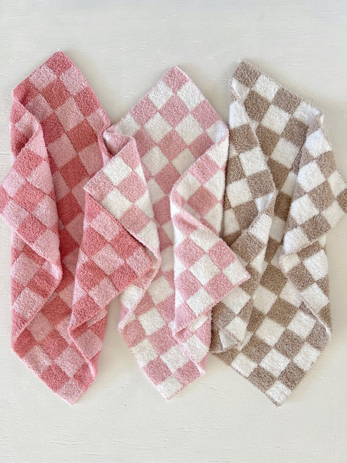 Four checkered towels in pink and brown tones arranged on a light surface.