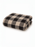 Folded beige and black checkered blanket on a white background. Soft texture, perfect for cozying up.