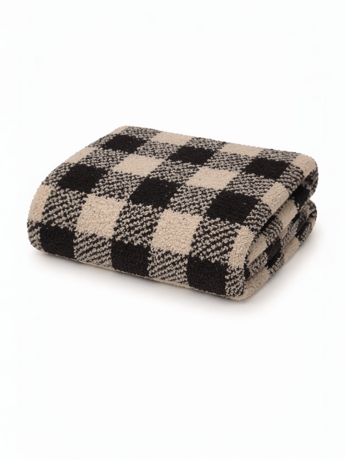 Folded beige and black checkered blanket on a white background. Soft texture, perfect for cozying up.