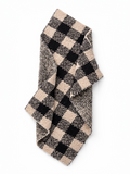 Checkered scarf in black and beige, folded on a white background. Ideal for winter fashion.