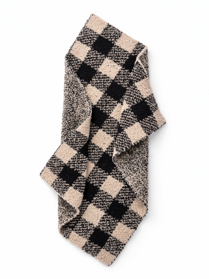 Checkered scarf in black and beige, folded on a white background. Ideal for winter fashion.