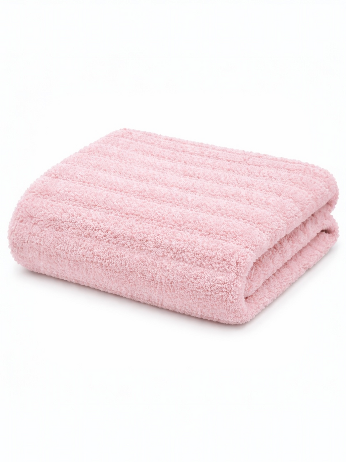 Soft pink bath towel neatly folded, featuring a textured design on a white background.