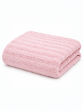 Soft pink bath towel neatly folded, featuring a textured design on a white background.