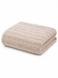 Folded beige towel on a white background, showcasing a soft, textured surface.