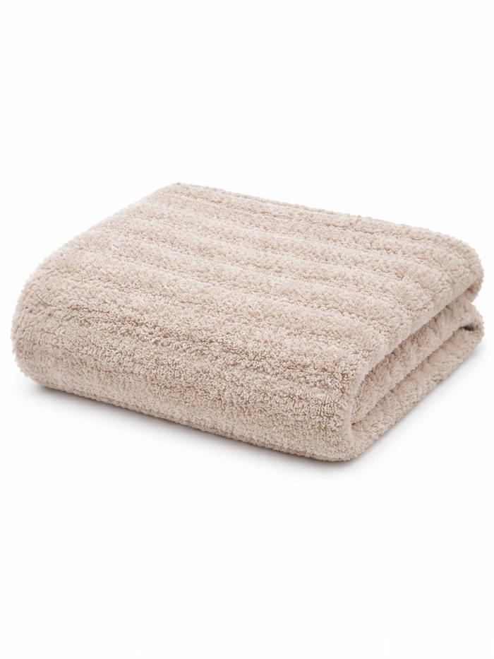 Folded beige towel on a white background, showcasing a soft, textured surface.