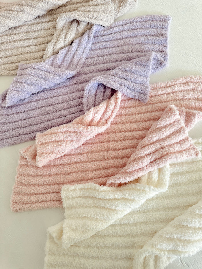 Colorful, soft, ribbed fabric in pastel shades of pink, lavender, and cream, arranged neatly on a light surface.