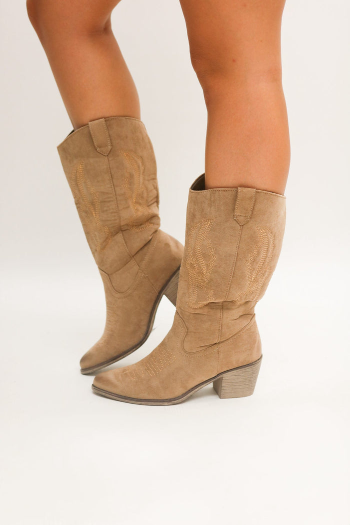 Tan knee-high boots worn by a person on a white background