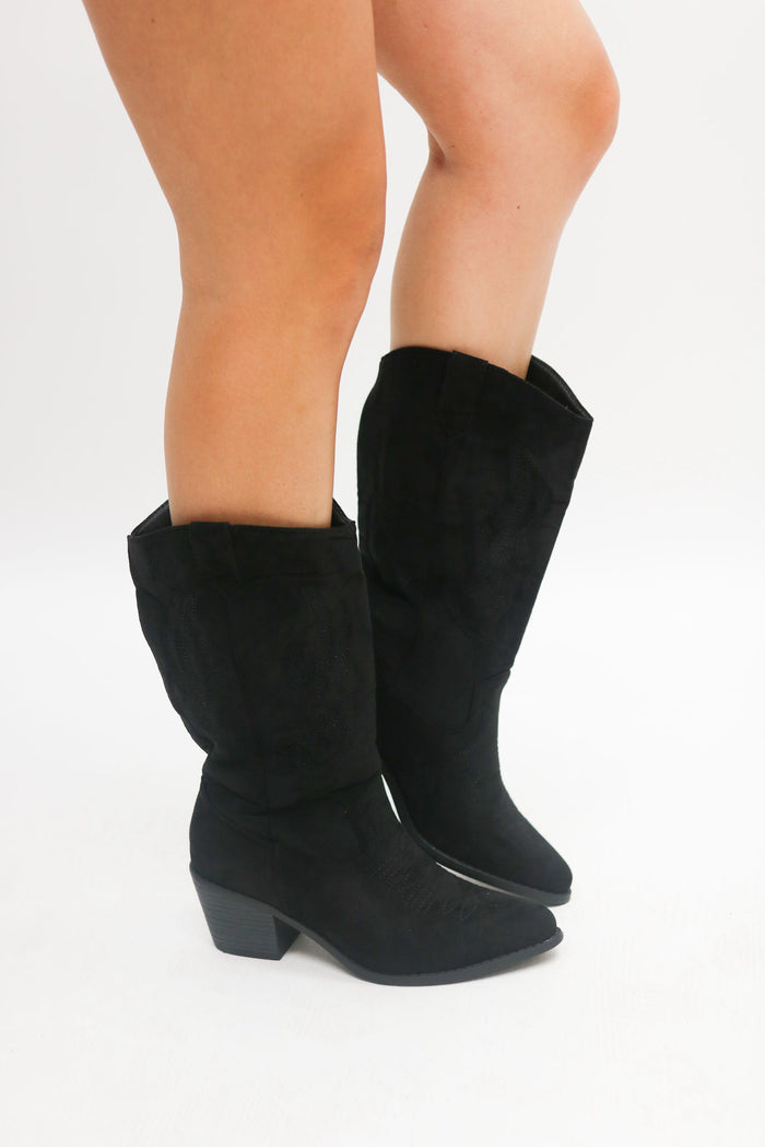 Black knee-high boots worn by a person on a white background