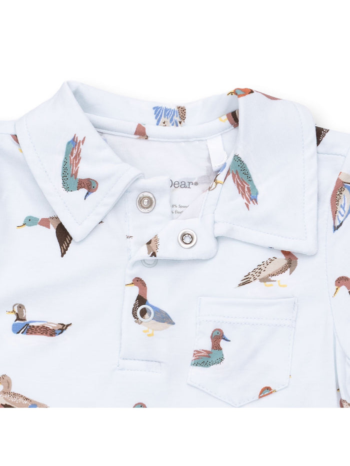 Light blue polo shirt with colorful duck prints and a front pocket. Ideal for casual wear.