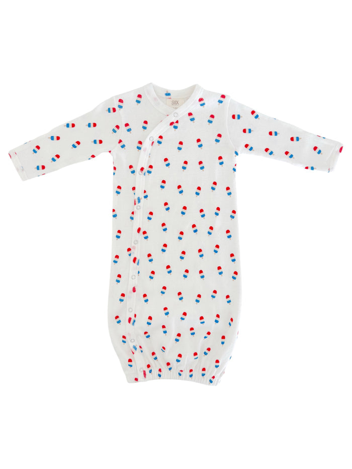White baby gown with colorful pill print, featuring long sleeves and snap closures at the front.