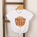 White t-shirt with "Pretty Neat" text design, displayed on a wooden rack against a beige wall.