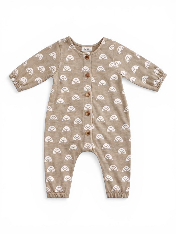 Tan baby romper with white rainbow patterns and wooden buttons, featuring long sleeves and elastic ankle cuffs.
