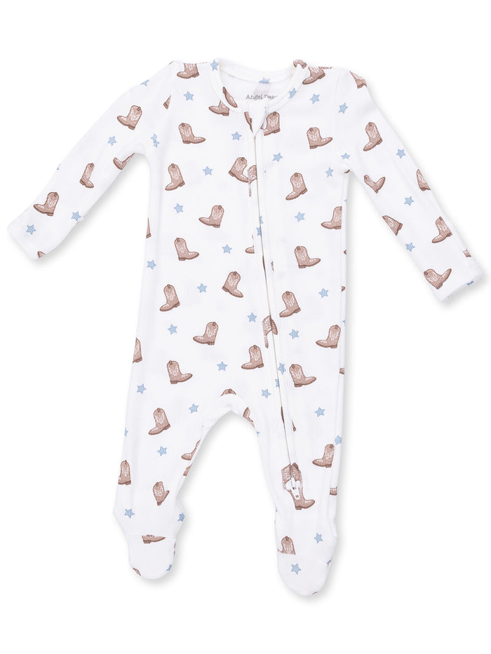 White infant onesie with brown cowboy boots and blue stars pattern, featuring long sleeves and a front zipper.