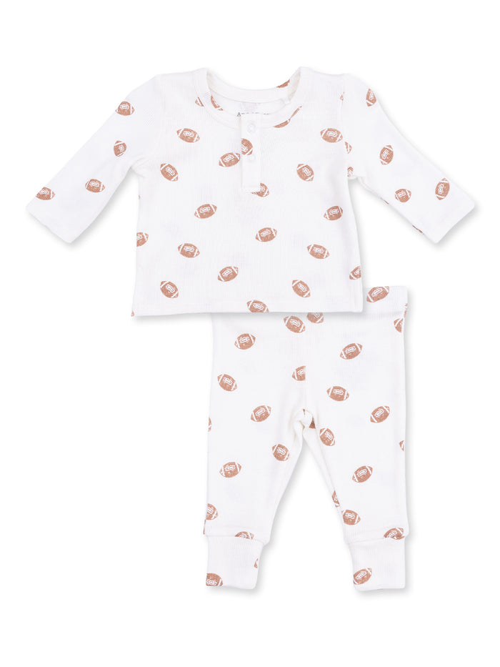 White baby outfit featuring a long-sleeve top and pants with a football print.