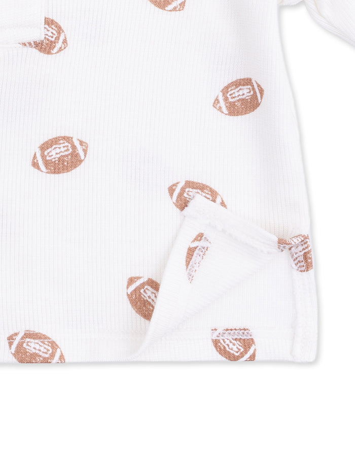 White fabric with brown football patterns, featuring a folded edge detail. Perfect for sports-themed outfits.