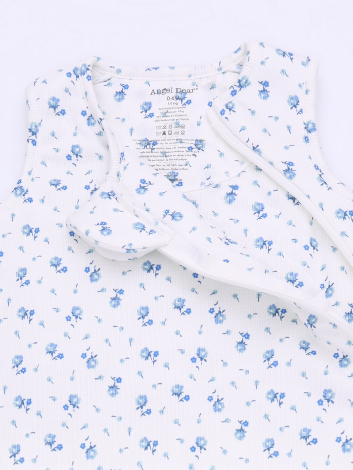 Floral-patterned baby outfit with soft fabric and tag details, featuring blue flowers on a white background.