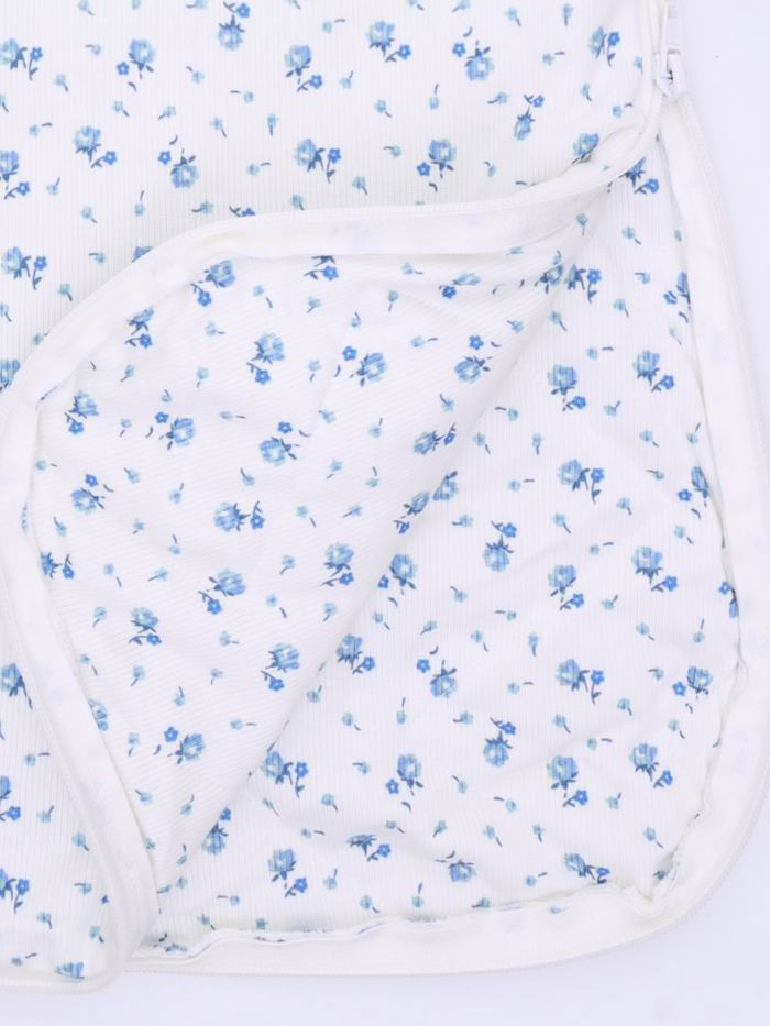 Floral patterned fabric with small blue flowers on a white background, partially folded over.