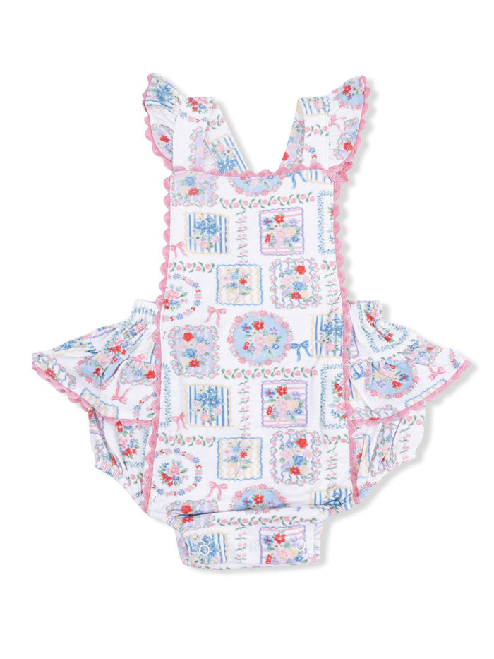 Floral patterned baby romper with ruffled straps and buttons at the bottom, designed for comfort and style.