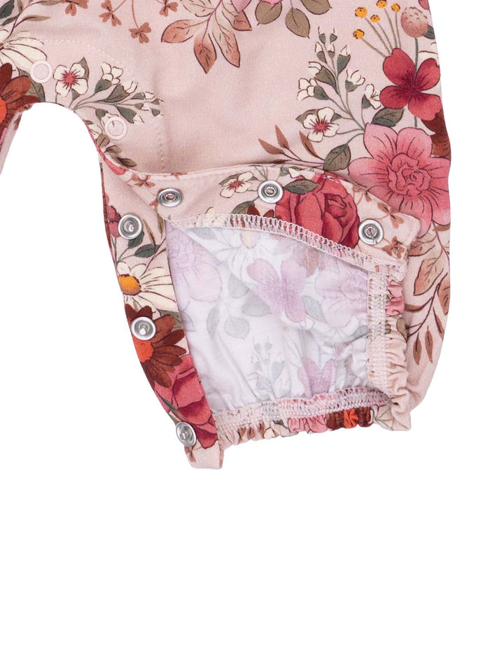 Floral-patterned infant romper with snap closure and contrast lining, featuring vibrant pink and peach colors.