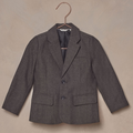 Gray children's blazer hanging on a rose gold hook against a textured background.