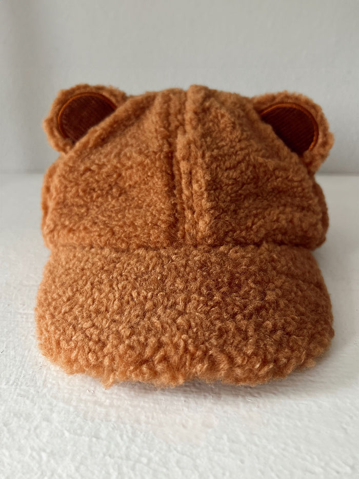 Brown bear-themed cap with fuzzy texture and ears, displayed against a white background.