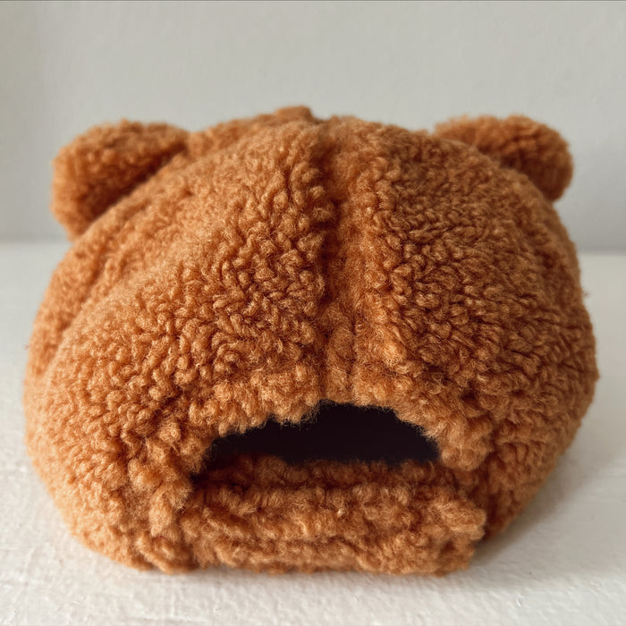 Brown bear-themed stuffed hat with fuzzy texture and ear details, viewed from the back.