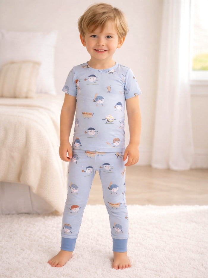 Smiling young boy in playful pajamas with cartoon patterns, standing in a bright, cozy bedroom.