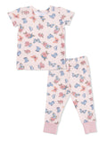 Pajama set for kids featuring short-sleeve top and pants with floral and butterfly print on a light pink background.
