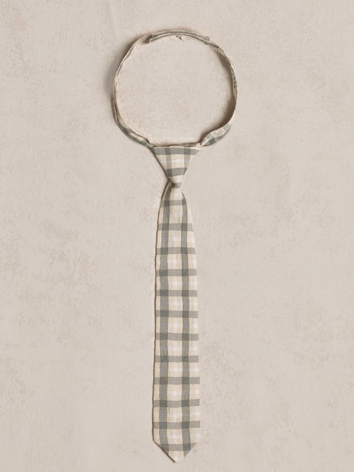 Gray and cream checkered tie laid flat on a light textured background.
