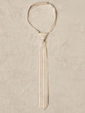 Beige striped tie displayed on a textured background.