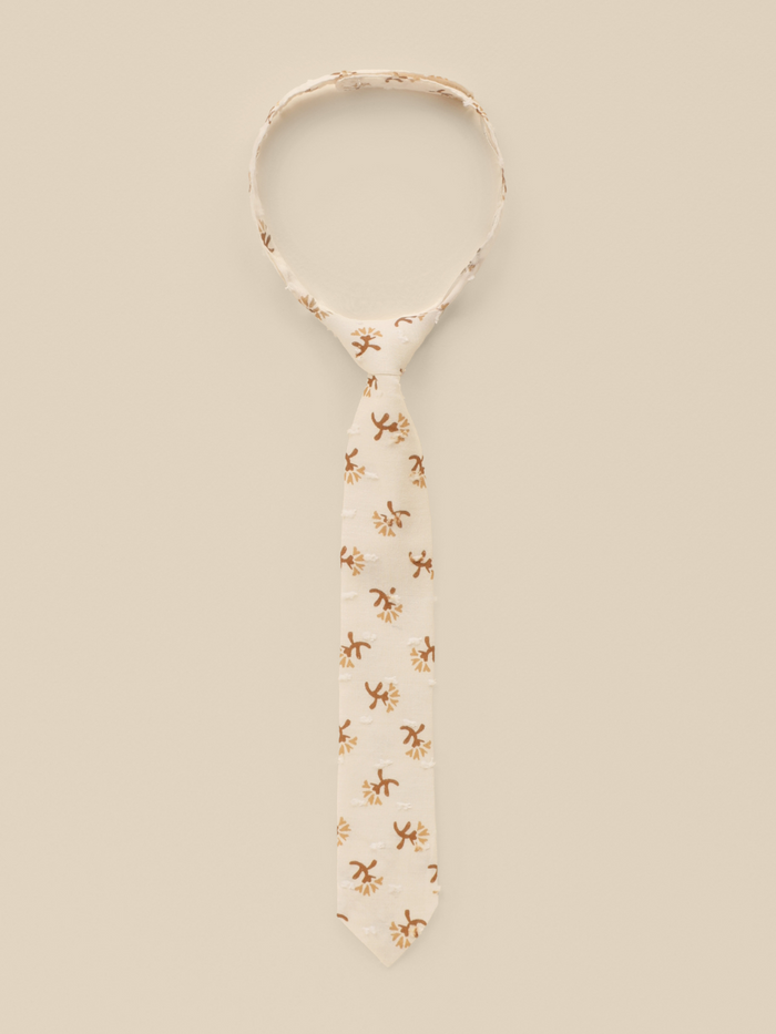 Beige tie with floral patterns on a light background, elegantly displayed for a stylish look.