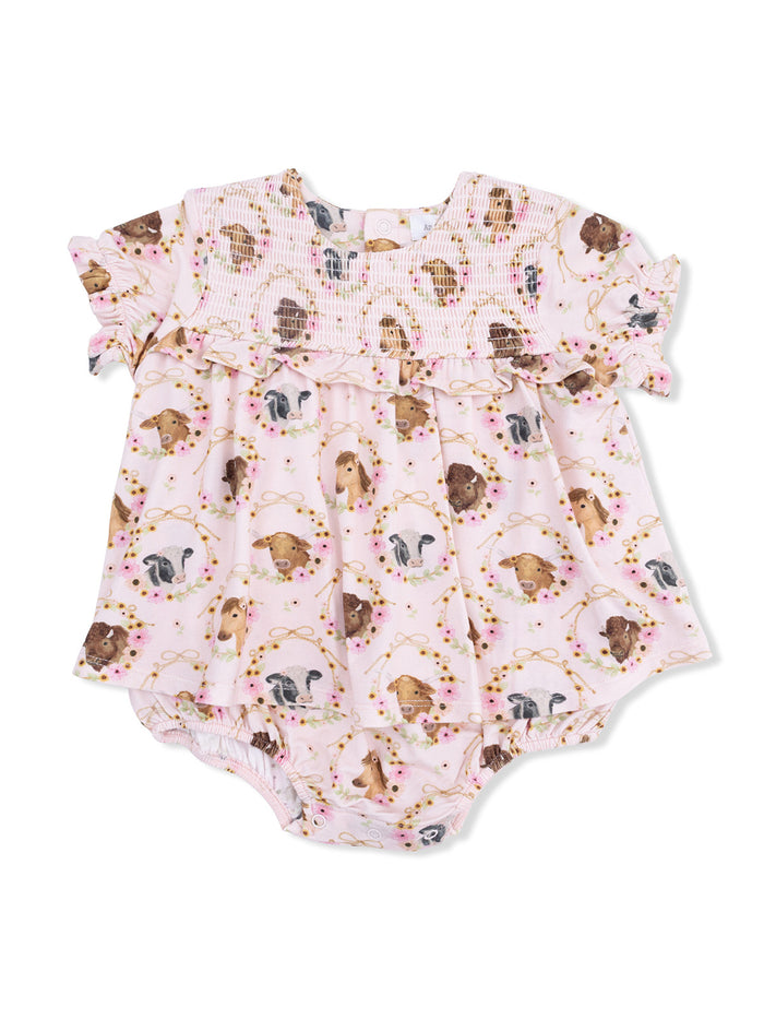 Light pink baby romper featuring various dog illustrations and floral accents with ruffled sleeves.