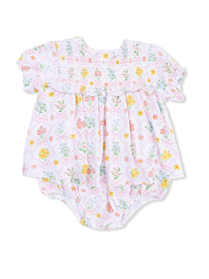 Floral baby romper with pink background and colorful flowers, featuring smocked yoke and ruffled sleeves.