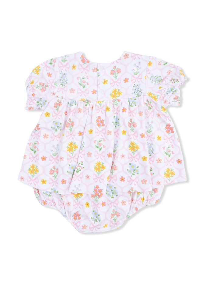 Floral-patterned baby romper with short puff sleeves and snap closure at the back, in pastel colors.