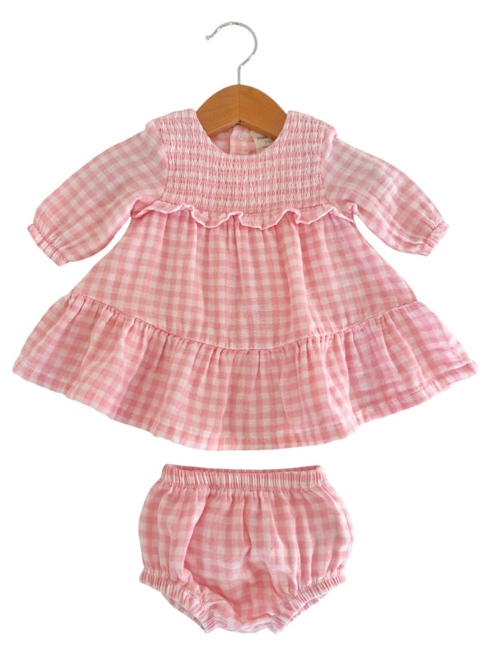 Pink gingham dress with matching bloomers hanging on a wooden hanger. Perfect for young children.