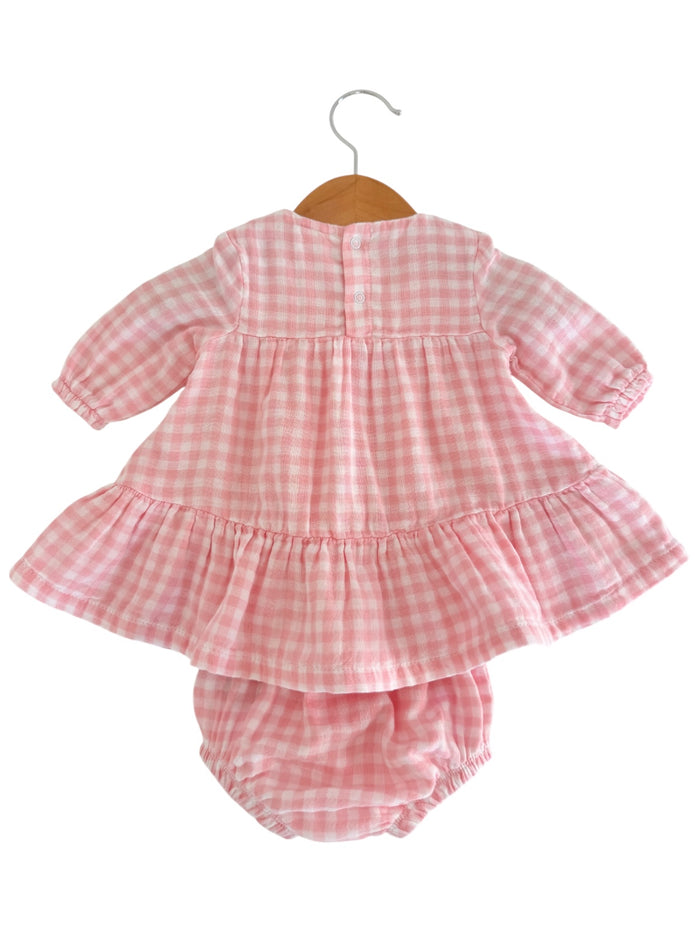 Pink checked dress with puff sleeves and matching bloomers, displayed on a wooden hanger. Ideal for baby girls.