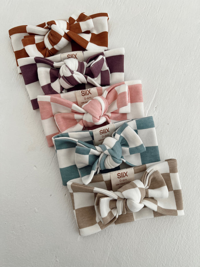 Six colorful checkered baby headbands arranged in two rows on a light background, showcasing various pastel shades.
