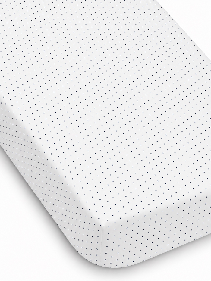White fitted sheet with navy blue polka dots, showcasing texture and neat edges. Ideal for bedding decor.