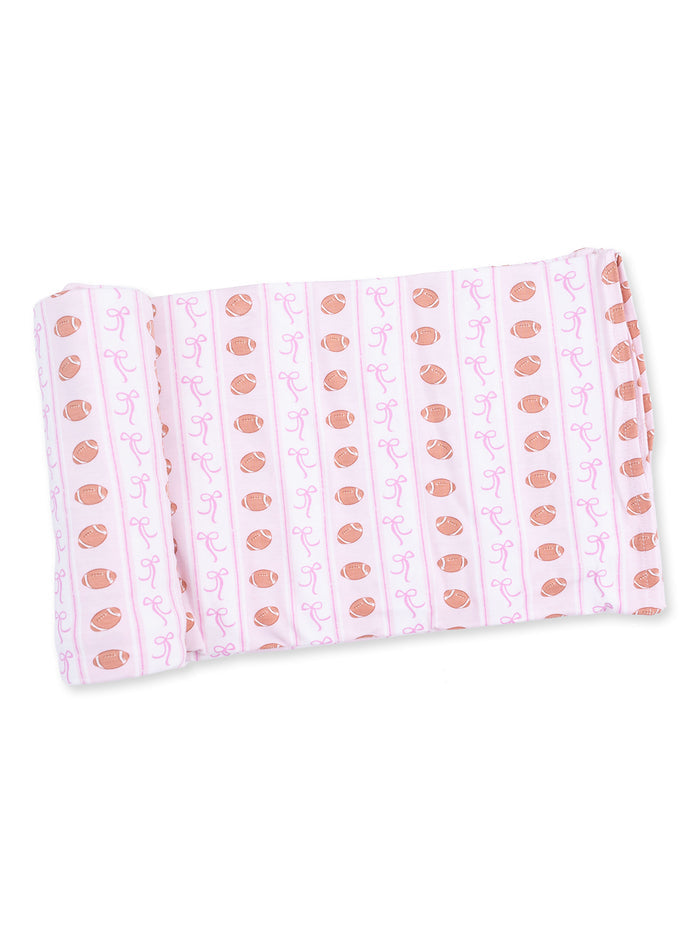 Pink fabric with football and ribbon pattern rolled neatly. Ideal for craft or sewing projects.
