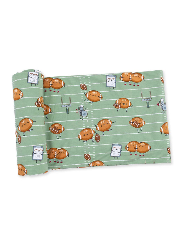 Green fabric featuring cartoonish footballs and playful characters on a football field design.