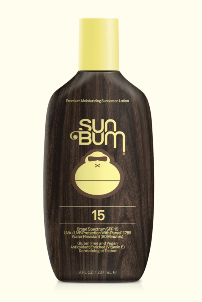 A series of four Sun Bum brand skin care products including sunscreen lotion, after sun cool down lotion, after sun cool down gel, and browning lotion, displayed outdoors.