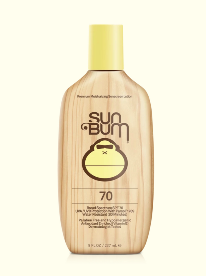 A series of four Sun Bum brand skin care products including sunscreen lotion, after sun cool down lotion, after sun cool down gel, and browning lotion, displayed outdoors.
