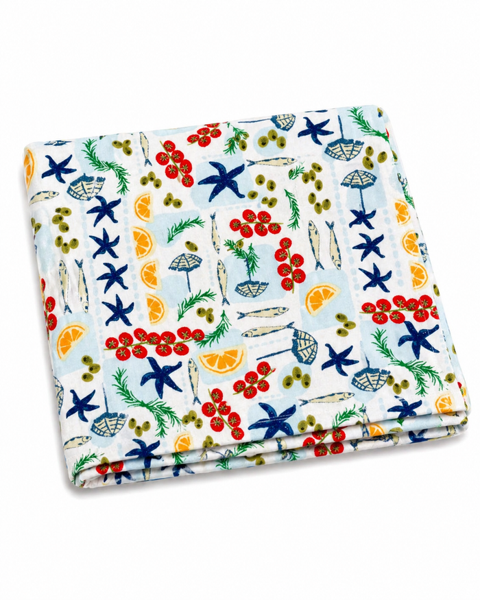 Colorful fabric featuring a seaside pattern with seashells, fish, olives, and citrus fruits.