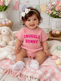 Smiling baby wearing a pink "Snuggle Bunny" outfit, surrounded by flowers, stuffed bunny, and pastel Easter eggs.