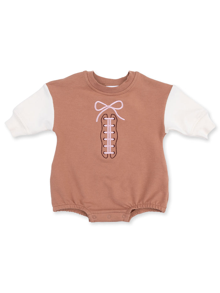 Brown baby onesie with white sleeves and a pink bow design resembling shoelaces.